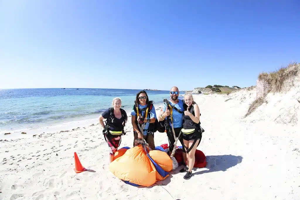 4 people smiling on the beach rottnest with parachute